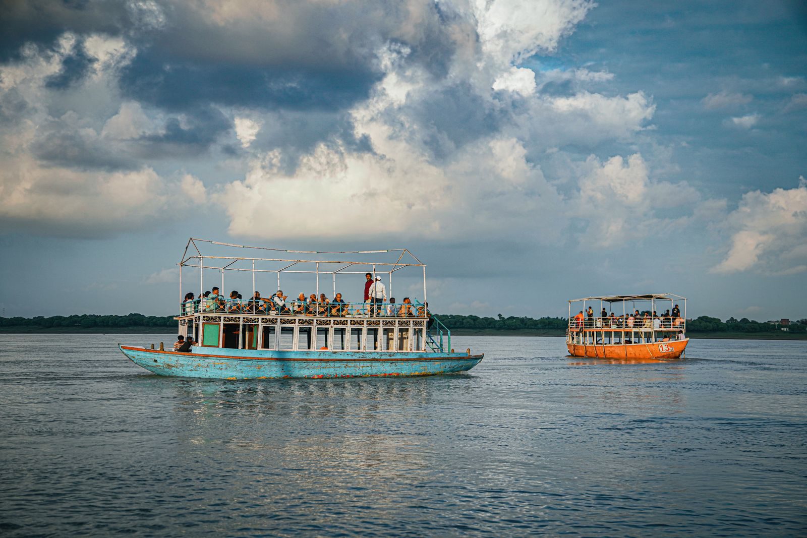 Tourist boats sailing on the Ganges River under dramatic clouds in Varanasi, India.