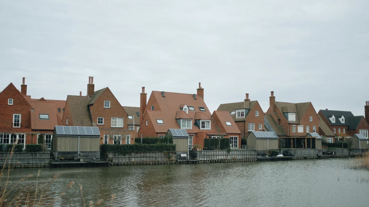 Schilderachtige rij van rode bakstenen huizen langs een rustige gracht onder een bewolkte lucht.